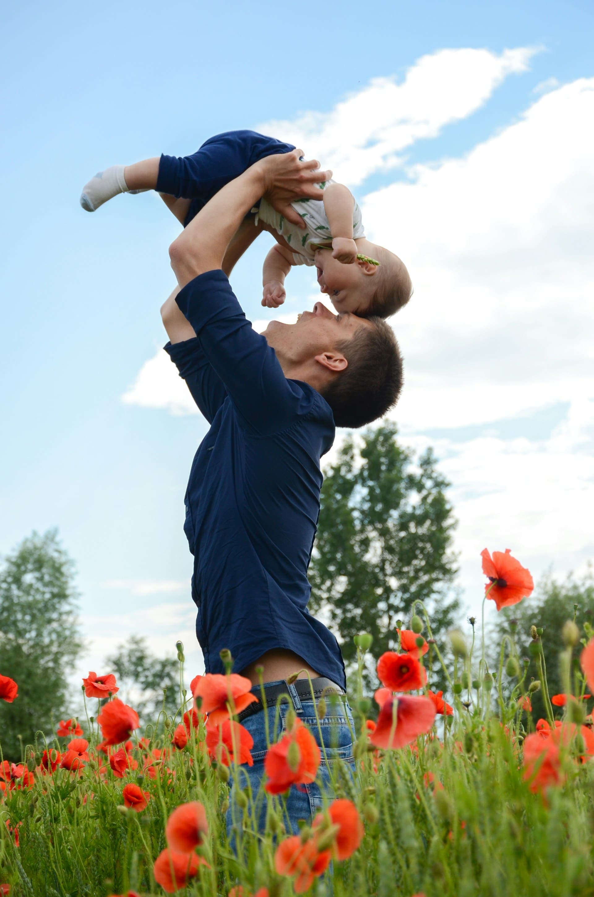 Vater hält sein Baby in einem Mohnblumenfeld