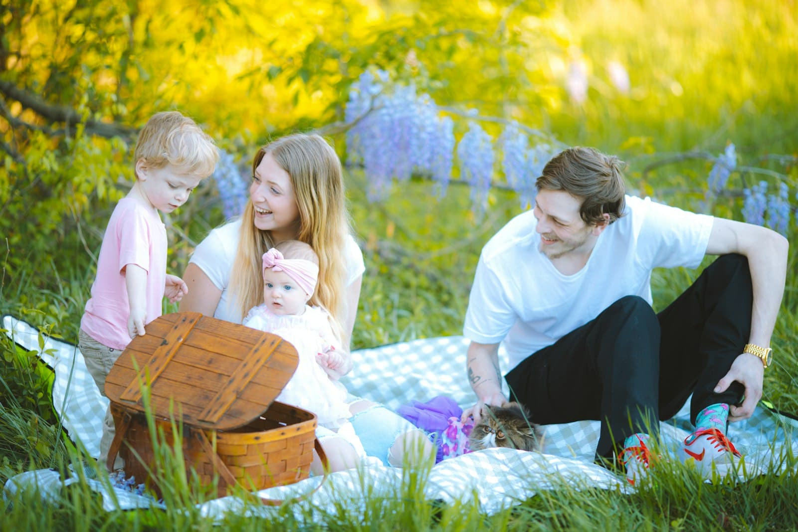 Familie mit zwei Kindern sitzt auf einer Picknickdecke im Grünen